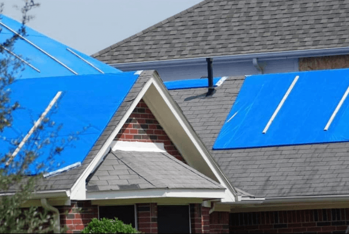 Blue tarps covering sections of a roof; Roof repair service by Pride Roofing LLC