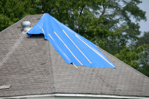 How To Protect Your Laurel MS Roof From Bad Weather with Pride Roofing LLC image of roof with blue tarp covering damage from storm