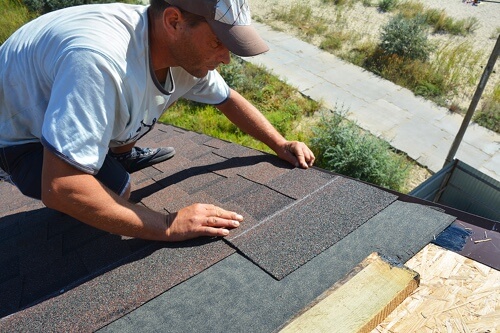 Pride Roofing LLC Offers Roofing In Albany, LA; image of roofer laying shingles on roof during the day