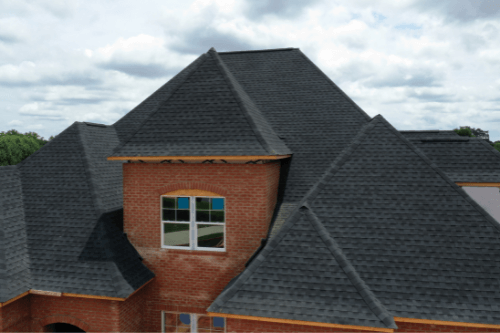 Roof Maintenance 101: How to Extend the Life of Your Shingles with Pride Roofing LLC. Aerial view of shingled roof of red brick home