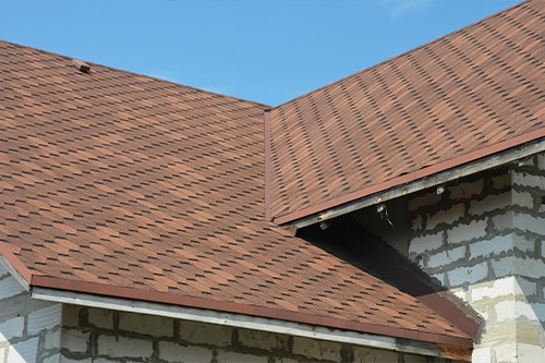 A close-up of an asphalt shingled roof valley with ventilation.