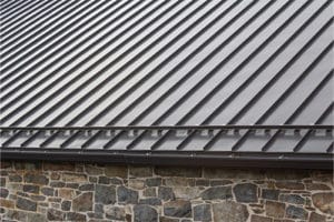 Standing seam modern metal roof over vintage stone wall, horizontal aspect