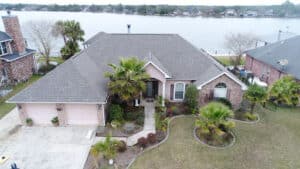 Pride Roofing LLC | Expert Roofing Services in Southeast Louisiana. Arial image of large size house on the lake with a new roof put on by Pride Roofing LLC.