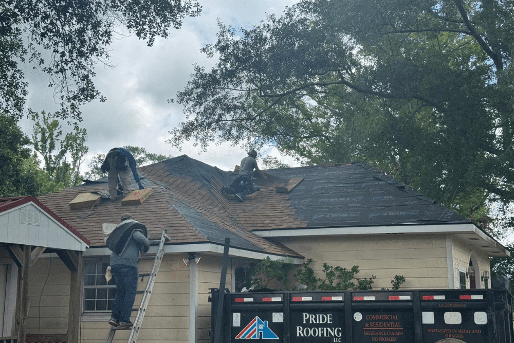 Professional roofers from Pride Roofing LLC in Hammond, LA, working on a residential roof replacement, with shingles being installed and roofing materials.