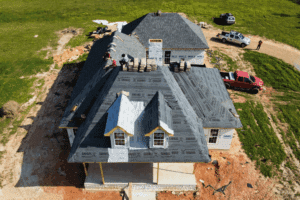 Roofing warranties, roofing services in Hammond, LA by Pride Roofing LLC. Aerial view of a new home under construction with workers installing shingles and underlayment, highlighting professional roofing craftsmanship and attention to detail on a sunny day.