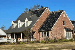 Hurricane roofing preparation, roofing services in Hammond, LA at Pride Roofing LLC. Image of Roofing contractors replacing asphalt shingles on a large brick home, showcasing residential roof replacement and storm damage roof repair services during hurricane season preparation.