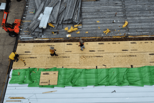 Roof replacement, roofing services in Hammond, LA by Pride Roofing LLC. Image of roofing professionals installing decking and preparing a commercial roof surface, showing tear-off and rebuilding stages of a flat metal roof replacement.